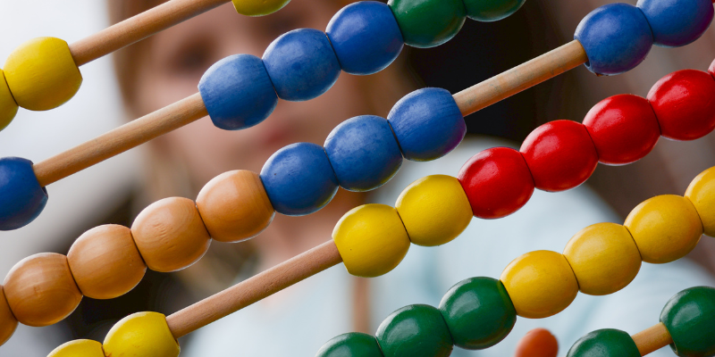 Close-up of a wooden abacus with a child blurred in the background