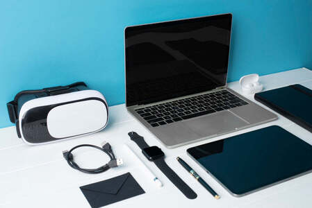 A laptop, tablet, smartwatch and VR headset laid out on a desk