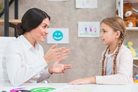 A therapist talking with a young girl using emotion cards