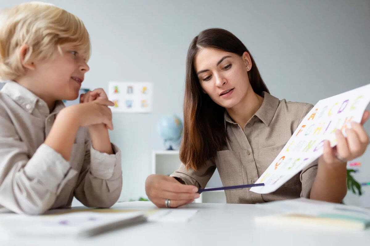 A therapist showing a boy colourful alphabet cards
