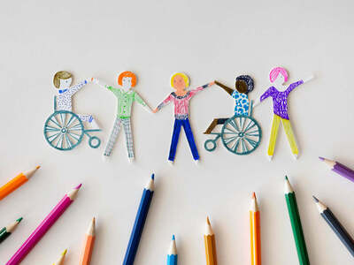 Paper cut-out figures holding hands, two seated in wheelchairs