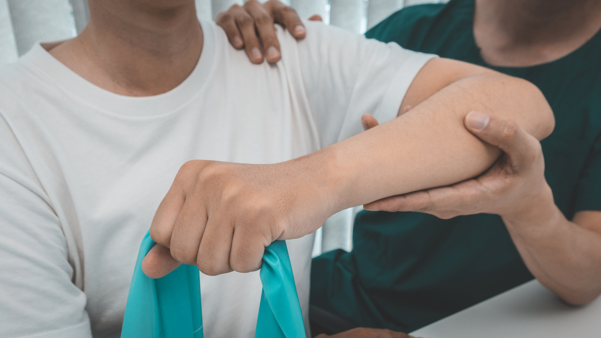 A therapist helping a client with a resistance-band arm exercise