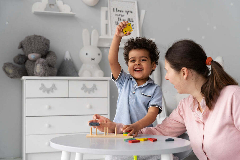 A mother and young boy playing with a wooden shape-sorting toy