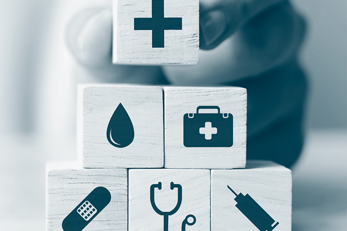 Wooden blocks stacked with medical icons like a cross and stethoscope