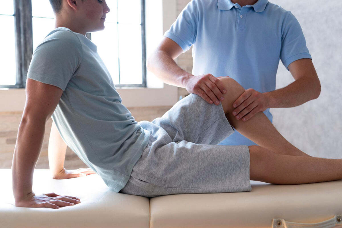 A physiotherapist assisting a client's knee movement on a treatment table