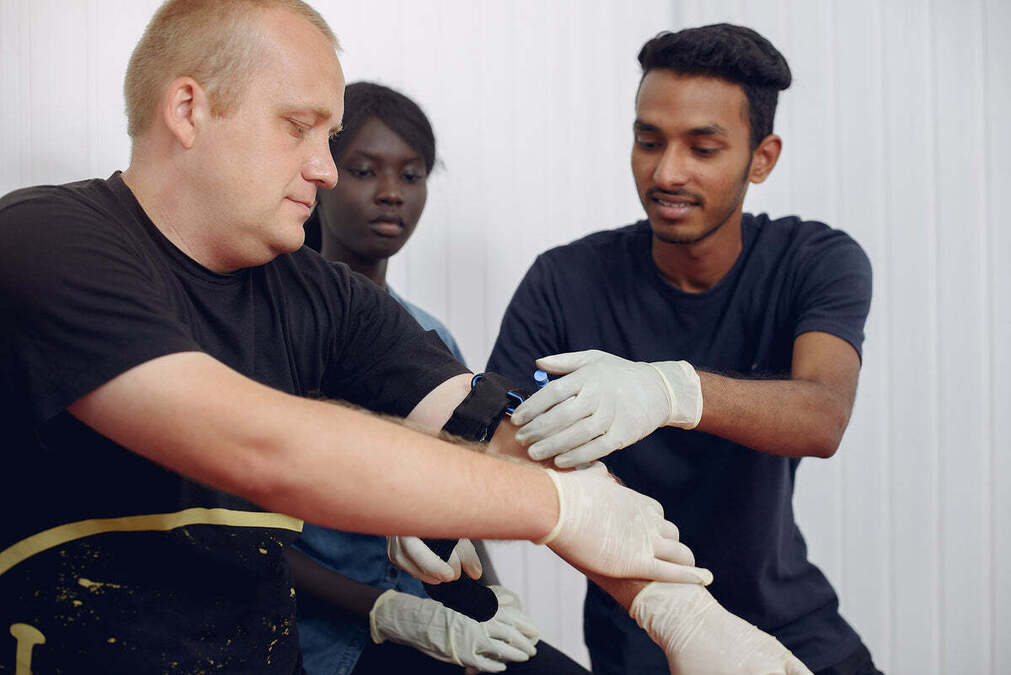 Two people wearing gloves fitting a wrist support on someone's arm